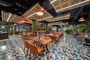 Un restaurante moderno con suelo de estampado geométrico, vigas de madera en el techo e iluminación colgante naranja.