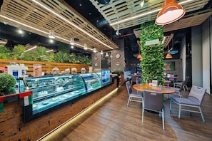 L’intérieur d’un café moderne, avec un comptoir en bois, un espace salon et des plantes décoratives.