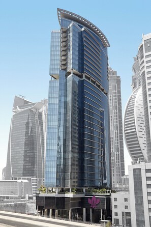 Un immeuble moderne de grande hauteur, doté d’une façade incurvée en verre, entouré d’autres bâtiments imposants.