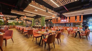 Un restaurant spacieux avec des tables et des chaises en bois, un coin bar et un plafond haut avec des poutres apparentes.