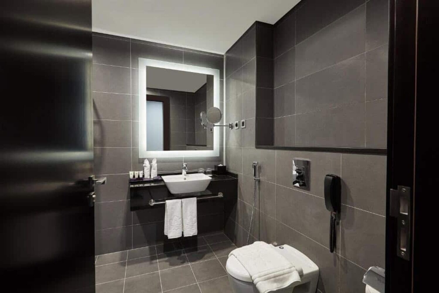 Une salle de bain moderne avec un grand miroir, un lavabo, des toilettes et une douche.