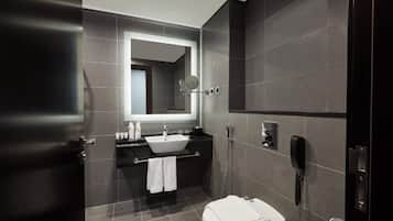 Une salle de bain moderne avec un grand miroir, un lavabo, des toilettes et une douche.