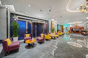 A modern lobby with seating areas, a reception desk, and a 'GOOD DAY' sign.