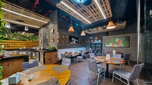 A modern restaurant interior with wooden tables, hanging pendant lights, and brick walls.