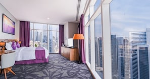 Une chambre d’hôtel avec un grand lit, un bureau, une télévision et une vue sur la ville.