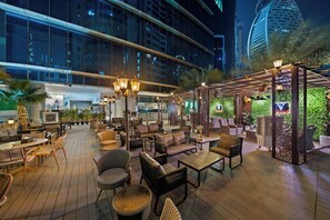 Un espace de détente extérieur comprenant des sièges, une pergola et une vue sur un bâtiment moderne.