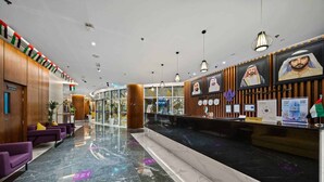 A hotel lobby with a reception desk, purple seating, and a marble floor.