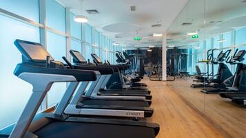 Une salle de sport équipée de tapis de course, de miroirs et d’appareils d’exercice.