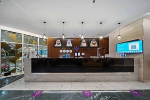 Un taulell de recepció d'hotel amb un disseny modern, amb superfície de marbre, panells de fusta i il·luminació penjant.