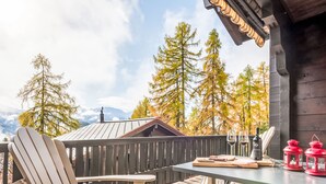 Eine Holzdielen-Terrasse mit Tisch, Stühlen, einer Weinflasche und roten Laternen.