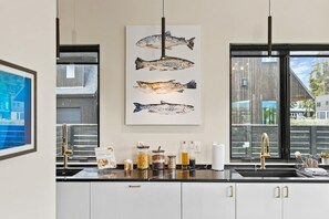 A kitchen with a black countertop, white cabinets, and a window with a view of a building. - Whitefish Modern Escape (Whitefish)