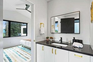 Une salle de bain moderne avec un grand miroir, deux lavabos et un ventilateur de plafond.