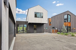 A modern building with a flat roof, large windows, and a gravel driveway. - Whitefish Modern Escape (Whitefish)