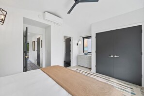 A hotel room with a bed, a dark wardrobe, a desk with a lamp, and a view of the outside. - Whitefish Modern Escape (Whitefish)