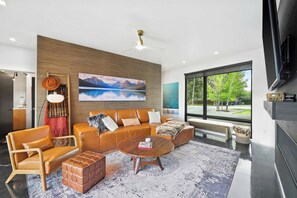 Un salon moderne avec un canapé, des fauteuils, une table basse et une cheminée.