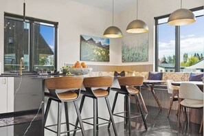 A modern kitchen with a central island, bar stools, and pendant lighting. - Whitefish Modern Escape (Whitefish)