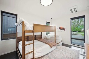 A bedroom with a bunk bed, a large window, and a view of the outdoors. - Whitefish Modern Escape (Whitefish)