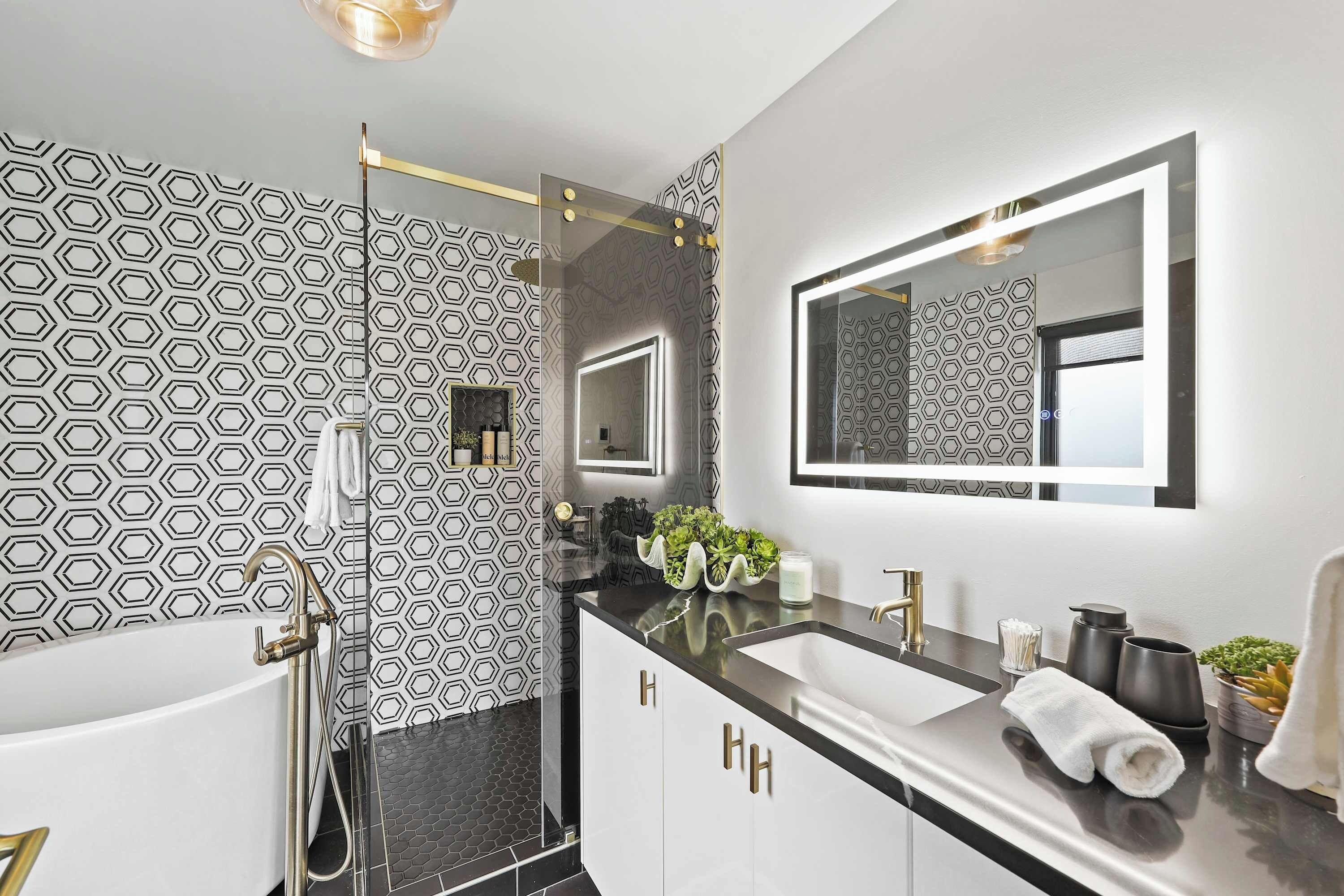 A modern bathroom with a black and white hexagonal pattern wall, a large mirror, and a dual sink vanity.