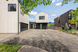 A modern residential area with three detached houses, a paved driveway, and a small garden area. - Whitefish Modern Escape (Whitefish)