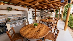 Ein Essbereich im Freien mit Holztischen und -stühlen, umgeben von einer rustikalen Holzpergola.