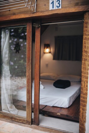 Quarto com uma cama, janela com cortinas e um número indicado acima.