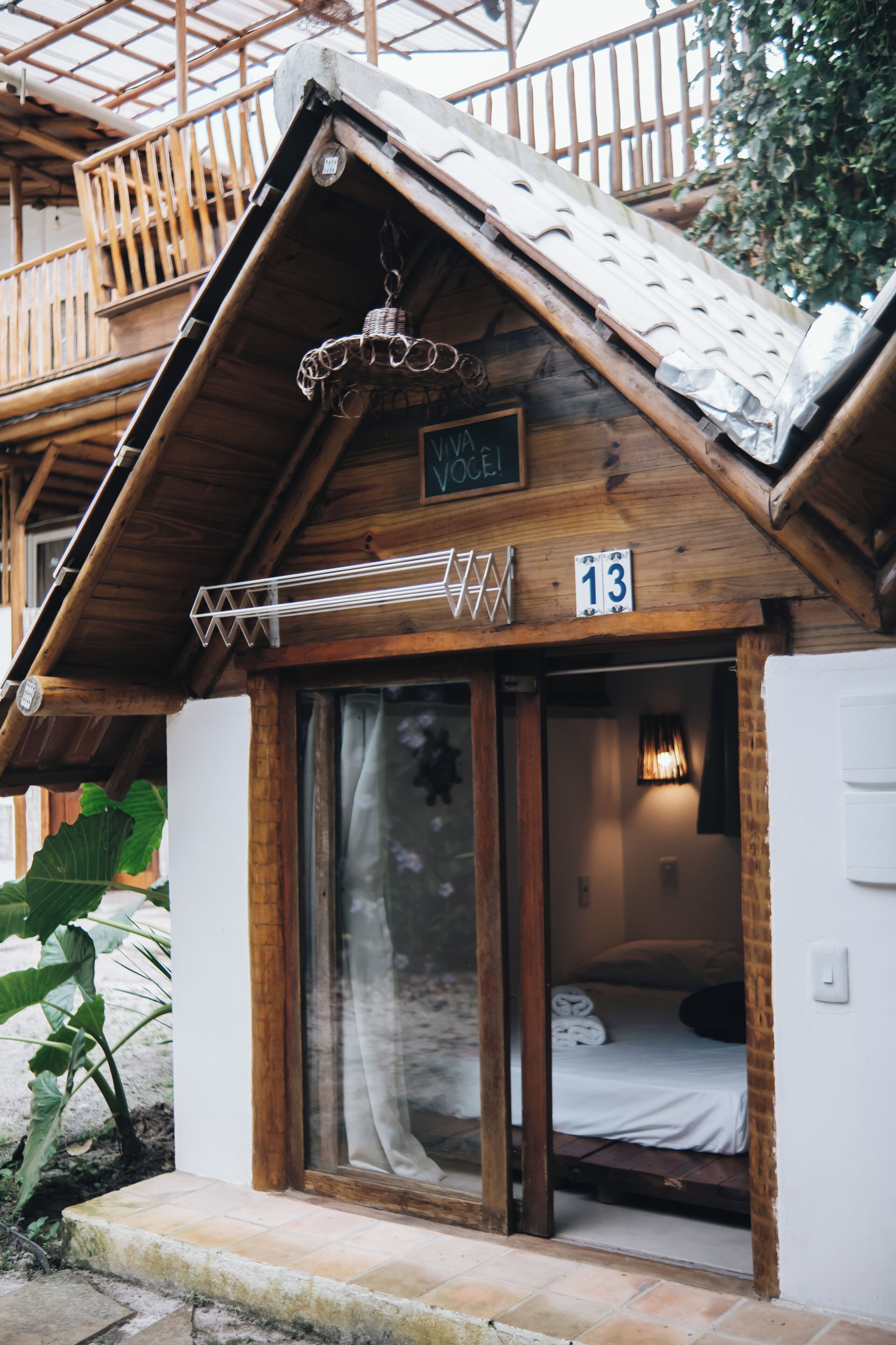 A wooden chalet with a balcony, a hanging light fixture, and a sign with the number 13.
