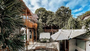 A pool area with a wooden deck, a small building with a tiled roof, and surrounding greenery. - Glamping Med (Porto Seguro)