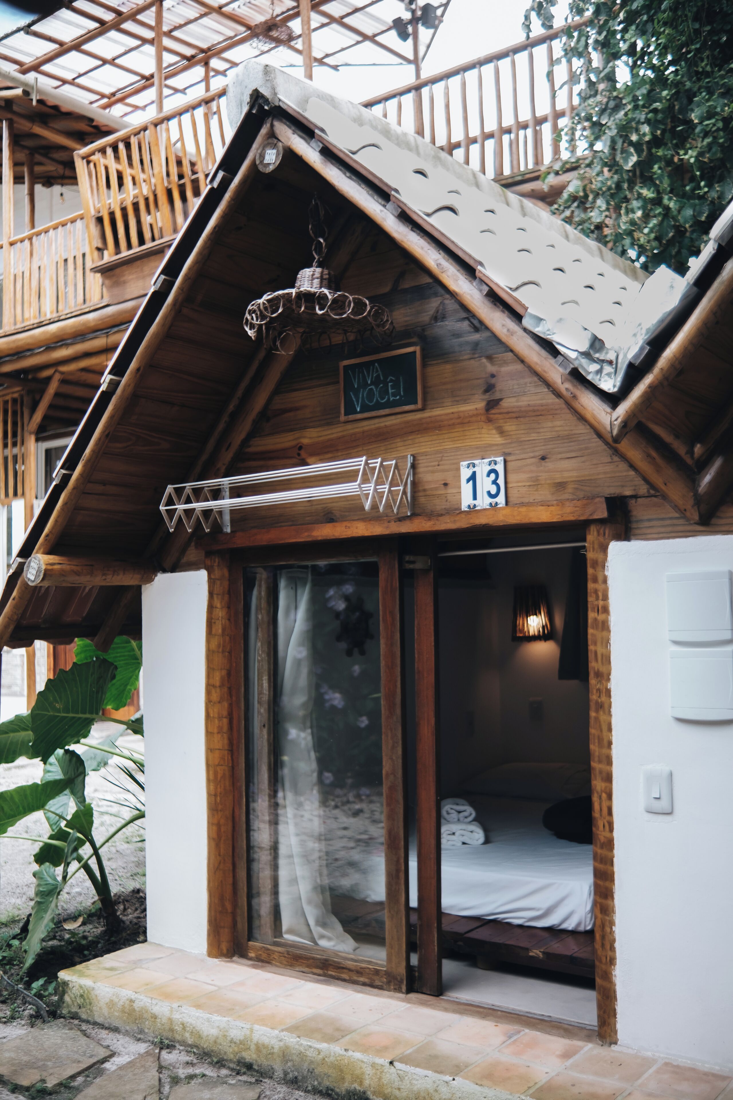 A wooden chalet with a balcony, a hanging light fixture, and a sign with the text 'VIVA VOCE!'