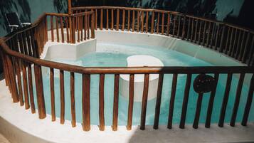 Ein Whirlpool mit Holzgeländer, umgeben von einer weißen Mauer.