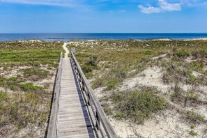 A wooden boardwalk leading to a beach with dunes and sparse vegetation. - Beautifully designed townhouse nestled in the wooded charm of Amelia Island (Fernandina Beach)