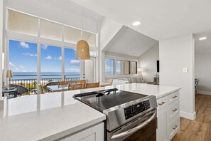 A modern kitchen with a large island, a built-in oven, and a view of the ocean. - Newly renovated oceanfront multi-level condo inthe Omni Resort Amelia Island (Fernandina Beach)