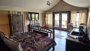 Ein geräumiges Schlafzimmer mit einem großen Bett, einem Holztisch und einem Balkon mit Vorhängen.