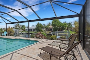 A pool area with lounge chairs, a clear view of the surrounding landscape, and a covered structure. - Villa Sandcastle 1003 Southern Exposure SW Cape Heated Pool Home w/ Kayaks (Cape Coral)