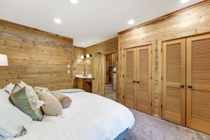 Une chambre avec un mur en bois, un lit avec des oreillers, une table de chevet et une armoire en bois.