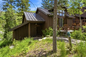 Un chalet rustique doté d’un toit en pente, d’une façade en bois et d’une terrasse avec des chaises.