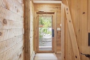A wooden interior hallway with a door leading to an outdoor area.