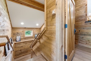 A wooden interior with a staircase, wooden walls, and a framed picture on the wall.