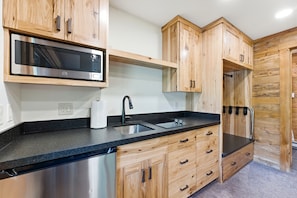 Een moderne keuken met houten kastjes, een RVS vaatwasser, een magnetron en een spoelbak.