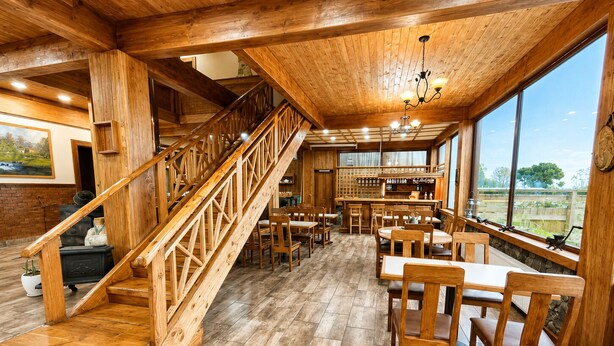 Un interior de madera con escalera, comedor y bar.