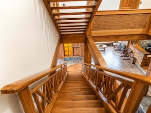 Una escalera de madera con un muro de ladrillo y una zona de estar debajo.