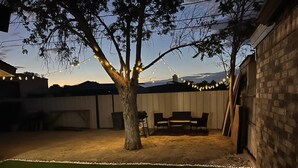 Ein Garten mit Baum, Gartenmöbeln und Lichterketten.