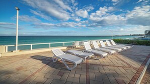 A seaside deck with lounge chairs, a railing, and a view of the ocean. - Elegant Stay Near the Beach 3403 (Cancún)
