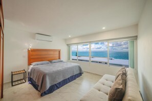 Ein Schlafzimmer mit Bett, einem Fenster mit Meerblick, einem Holzkopfstück und einem kleinen Tisch.