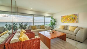 A modern living room with a sofa, a coffee table, and wicker chairs. - Elegant Stay Near the Beach 3403 (Cancún)