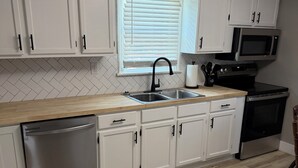 A kitchen with white cabinets, a stainless steel dishwasher, a microwave, and a black oven. - Charming recently renovated house with AC, WiFi, in The Ashtabula Harbor (Ashtabula)