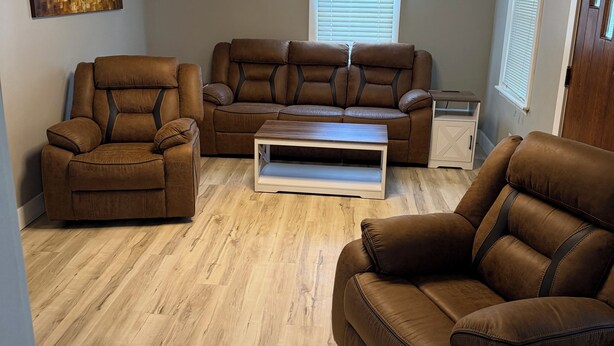 A living room with a brown leather sofa, a brown leather armchair, and a wooden coffee table. - Charming recently renovated house with AC, WiFi, in The Ashtabula Harbor (Ashtabula)