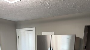 A kitchen with a stainless steel refrigerator, a wooden dining table, and a white door. - Charming recently renovated house with AC, WiFi, in The Ashtabula Harbor (Ashtabula)