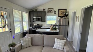 Una cocina moderna con electrodomésticos integrados, un sofá gris con cojines estampados y una mesa de centro de madera.