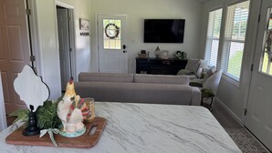 Un salón con una mesa de mármol, un sofá, un televisor y una puerta adornada con un adorno navideño.