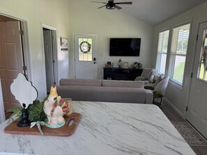A living room with a marble table, a sofa, a television, and a door with a wreath.